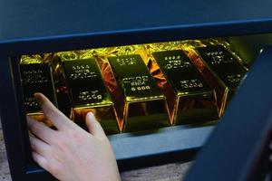 Hand open electronics steel safe box full of coins stack and gold bar photo