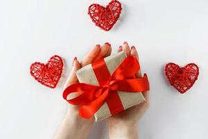 Gift with a red ribbon in hands on a white background photo