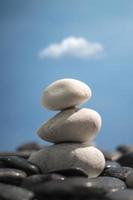 A pile of three white stones isolated on blue sky background. photo