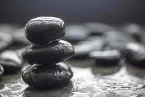 A pile of three Black stones isolated in blurred background. photo