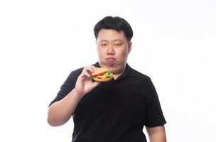 Young funny fat Asian man holding hamburger