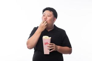 Joven gracioso gordo asiático comiendo palomitas de maíz foto