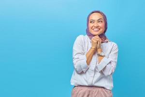 Asian woman looking cheerfully aside with folding raised hand photo