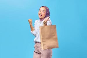 Sonriente joven estudiante universitario árabe mostrando bolsas de la compra.