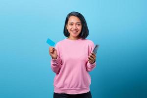 Asian woman holding smartphone and happy showing credit card photo