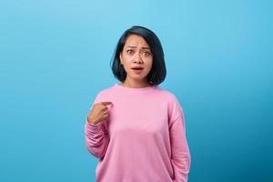 Retrato de mujer asiática sorprendida haciendo preguntas y apuntando a sí misma foto