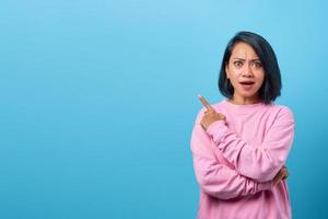 Attractive asian woman shocked and pointing finger to empty space photo
