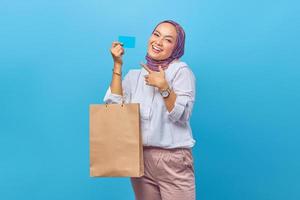 Portrait of happy young girl holding shopping bag and credit card