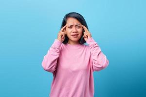 Retrato de mujer asiática tocando su cabeza y expresando preocupación foto