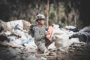 pobre niño recogiendo basura en su saco para ganarse la vida.