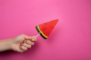 Watermelon sweet lollipop candy in a woman's hand. photo