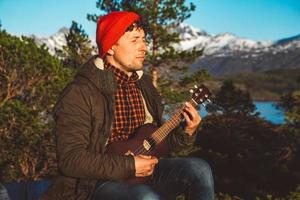 Guy playing guitar against the background of mountains, forests photo