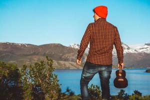 Guy with a guitar on the background of mountains, forests and lake photo