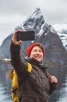hombre tomando selfie con montañas detrás de él