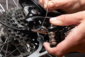 Tightening the gear shift cable on a bicycle with multitool. photo