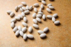 Las píldoras de vitamina D yacen caóticamente contra una encimera de arena.