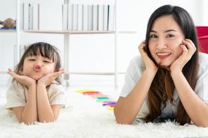 Mother and daughter laying on carpet photo