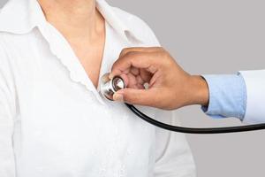 Doctor using stethoscope to listen heart photo