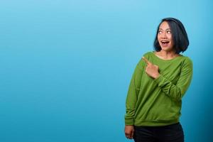 Attractive Asian woman shocked and pointing finger to empty space photo