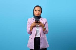 Hermosa mujer asiática piensa en algo mientras sostiene el teléfono móvil foto