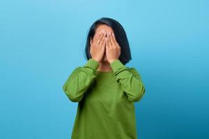Attractive Asian woman with sad expression covering face with hand photo