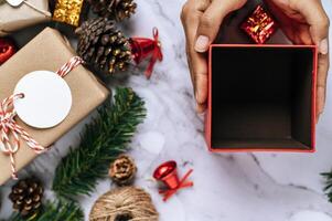 A hand holding a black gift box on a white cement floor photo