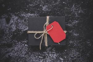 una caja de regalo negra colocada sobre un fondo de yeso negro.