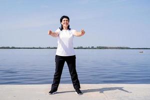 mujer mayor activa y feliz haciendo ejercicio cerca de la orilla del río foto