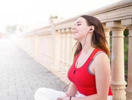 Teenage girl sitting next to column fencing listening to the music photo