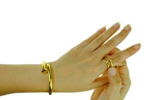 Mano de mujer con una pulsera de oro y un anillo de joyería. foto