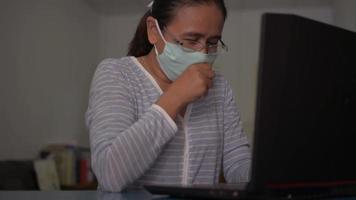 vrouw draagt gezichtsmasker hoestend tijdens het werken aan het bureau thuis video