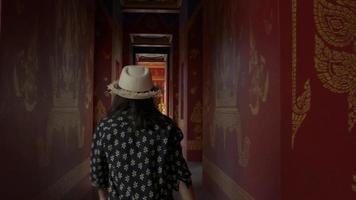 Touristin trägt Strohhut, der auf dem Flur im Tempel spazieren geht video