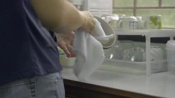 Asian woman wiping and cleaning ceramic bowls with a towel the kitchen