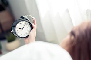 Young woman turn off alarm clock in morning. photo