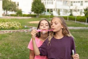 Two girls blowing soap bubbles - carefree and fun time and friendship photo