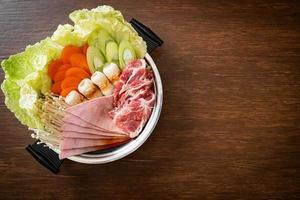 sukiyaki o shabu sopa negra de olla caliente con carne cruda y verdura foto