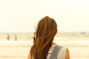 The traveler stand on the sand beach and look people are swimming photo