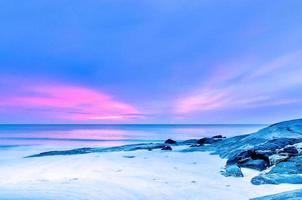 la vista de la playa de arena y las olas del mar con rocas y arrecifes en la mañana foto