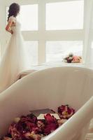 Bride with bath tub filled with flowers photo