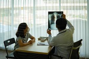 Doctor showing x-ray to patient with masks on photo