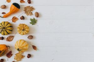Pumpkins, dried leaves on white wooden background top view. Autumn. photo
