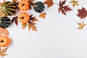 Pumpkins, dried leaves on a white wooden background. photo