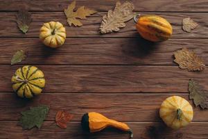 Pumpkins, dried leaves on white wooden background top view. Autumn. photo