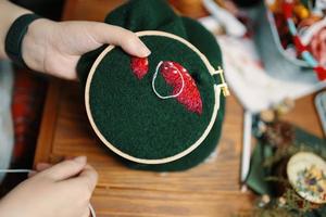 Women's hands embroiders fly agaric hat on frame photo