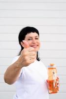 Woman showing thumbs up standing outdoors on gray solid background photo