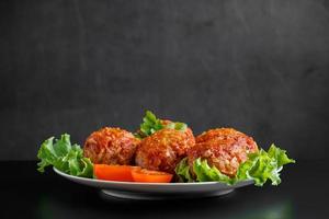 Meat balls in tomato sauce on a black background. photo