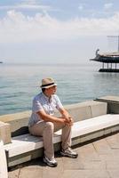 joven sentado en el banco junto al mar foto