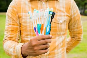 Man holding Old colorful toothbrushes on nature background photo