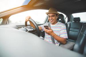 Young asian man using smartphone while driving car photo