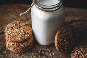 Cereal cookies with a jug of milk on a wooden background.